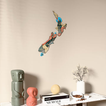 Sage New Zealand wooden wall map on a beige wall above a console with figurines