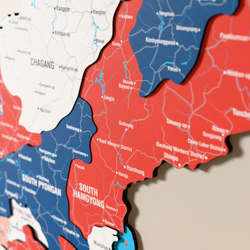 Close-up of the Flag colored North Korea wooden wall map with layered regions and printed names