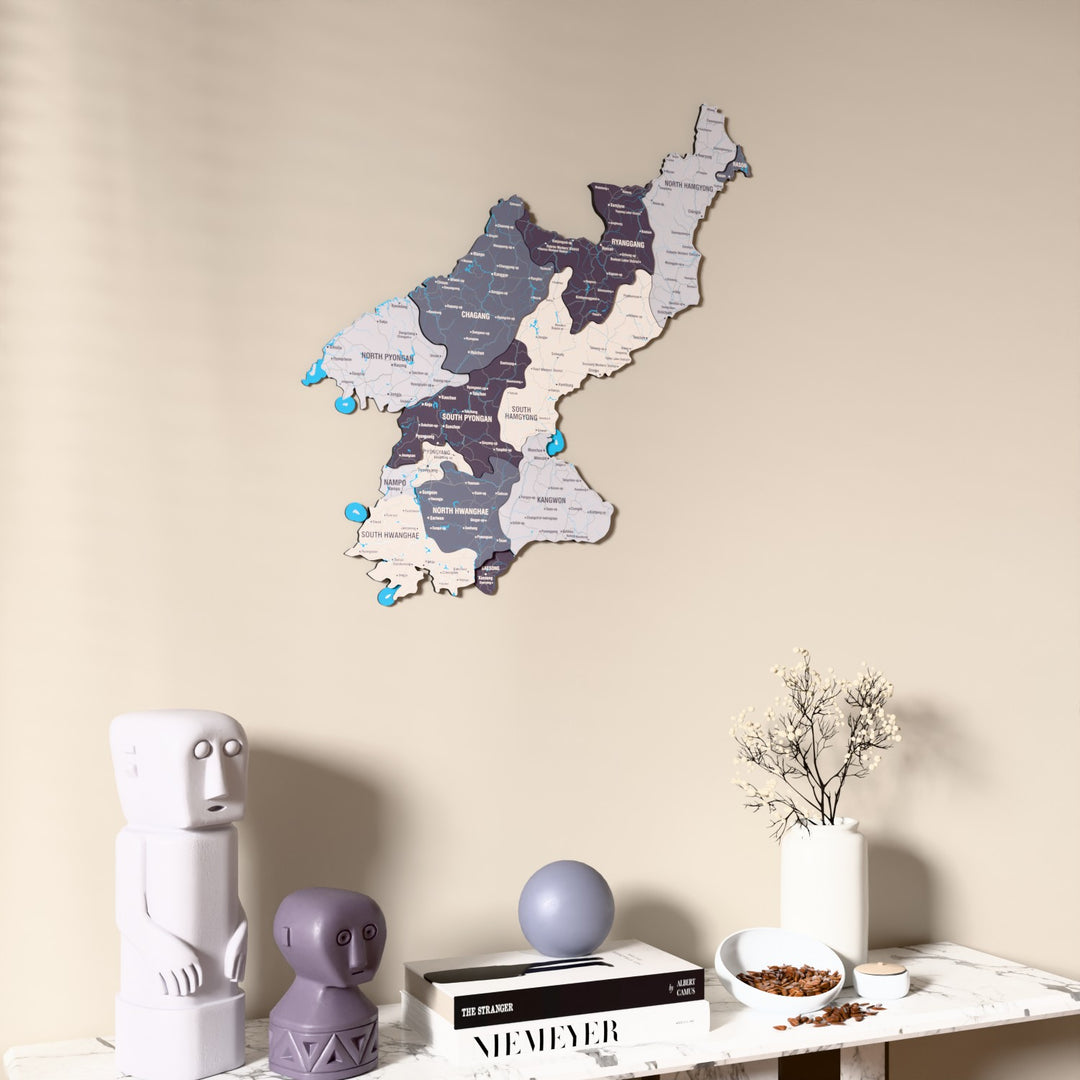 Nimbus North Korea wooden wall map on a beige wall above a console with figurines