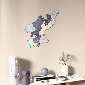 Nimbus North Korea wooden wall map on a beige wall above a console with figurines