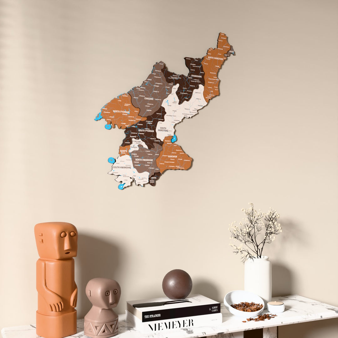 Soil North Korea wooden wall map on a beige wall above a console with figurines