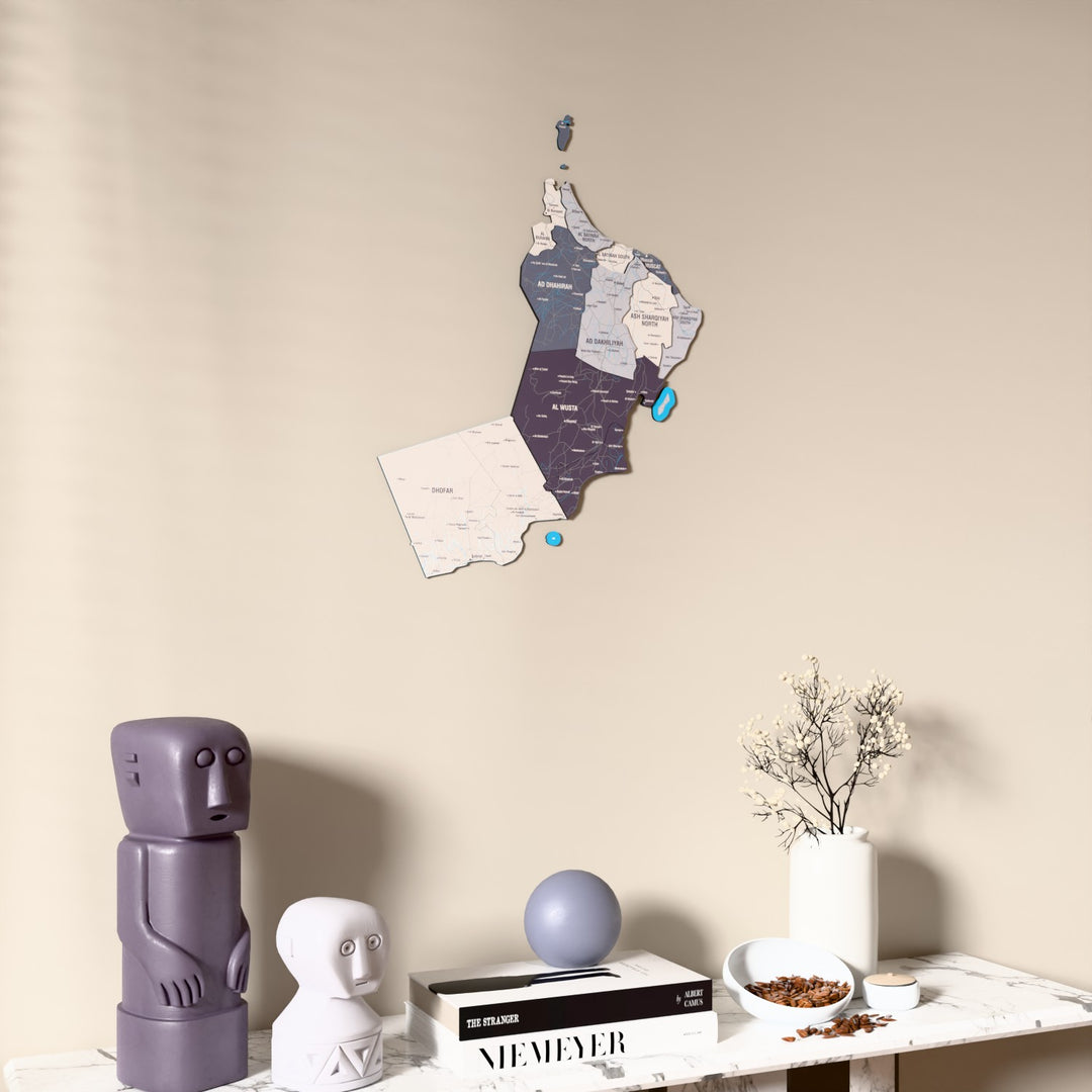 Nimbus Oman wooden wall map on a beige wall above a console with figurines