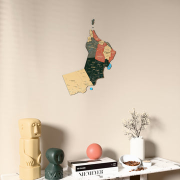 Sage Oman wooden wall map on a beige wall above a console with figurines