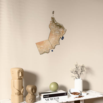 Satellite Oman wooden wall map on a beige wall above a console with figurines