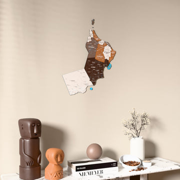 Soil Oman wooden wall map on a beige wall above a console with figurines