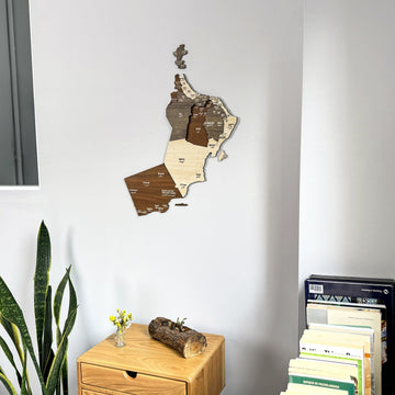 Oman wooden wall map near stacked books, tight view of the upper map and the drawer table