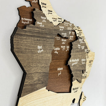 Close-up of the layered wood regions and Arabic and English city names on the Oman wooden map