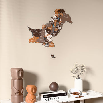 Soil Pakistan wooden wall map on a beige wall above a console with figurines