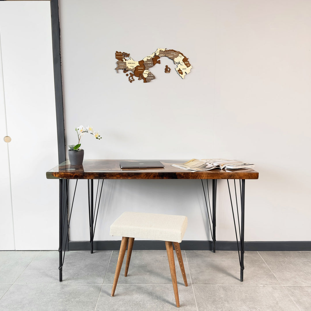 Wooden Panama map high on a white wall above a desk with a cream stool