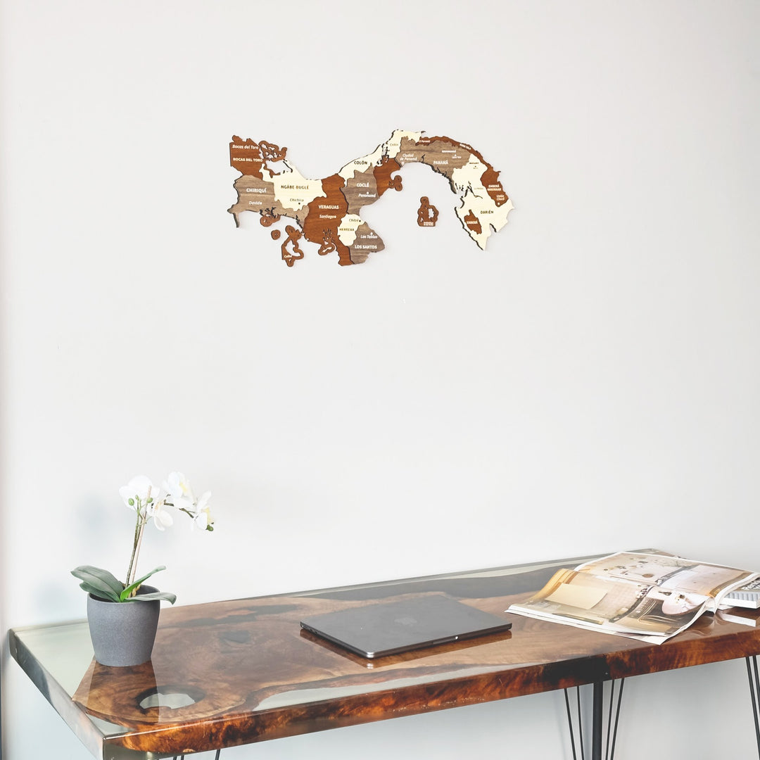 Wooden Panama map on a plain wall above a desk with an orchid