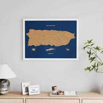 White-framed Puerto Rico cork wall map, straight-on above a lamp and framed pictures