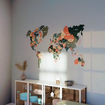 Sage metal world map on a blue-gray wall above a white cabinet with turquoise plates and a pampas stem
