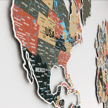 Close-up of North America on the sage metal world map, showing USA and Mexico in green, terracotta and tan