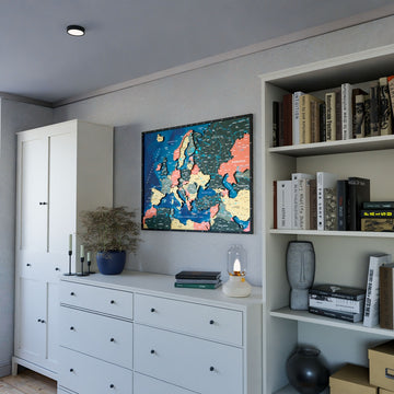 Wooden Europe map with rivers in Sage, above a white dresser beside a bookshelf