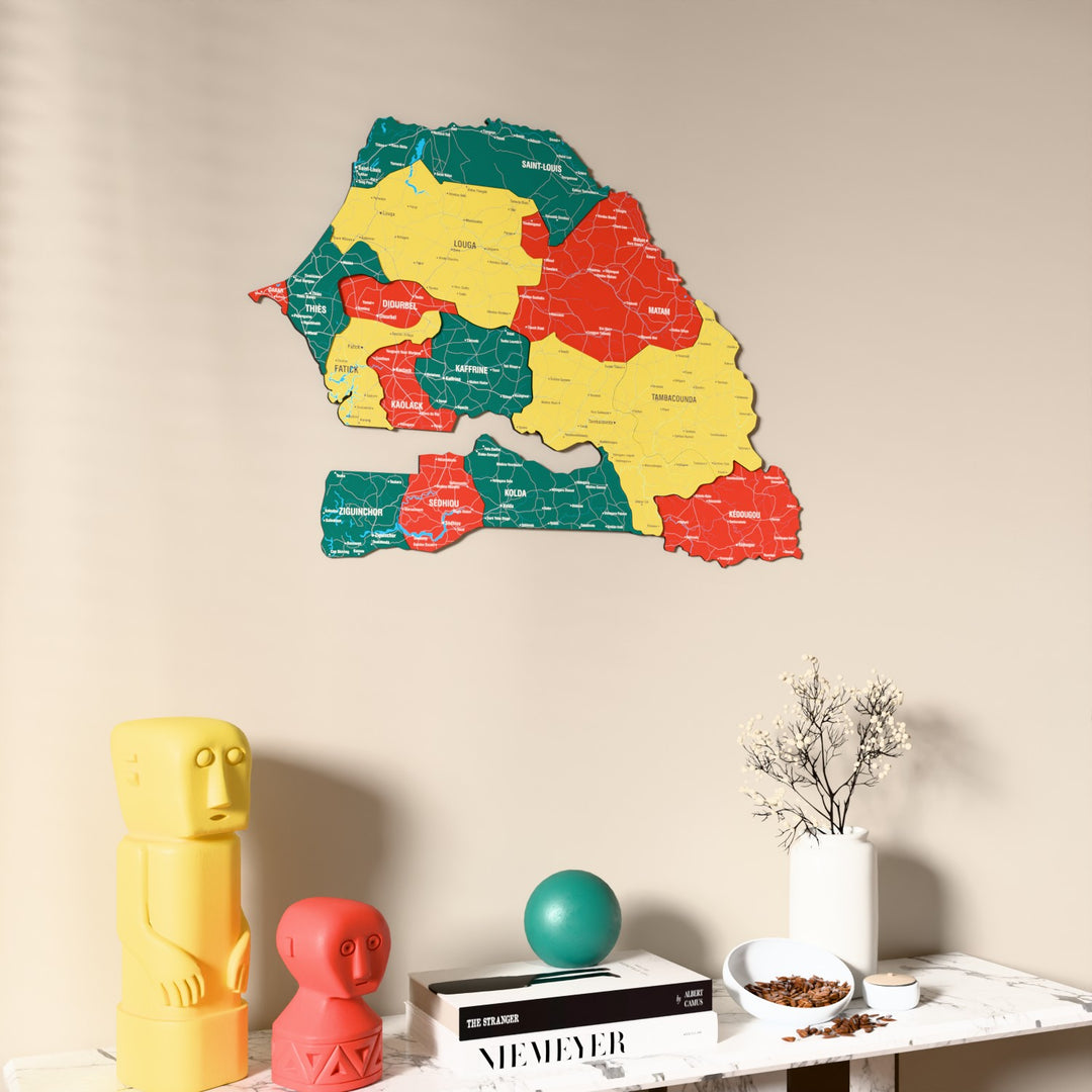 Flag colored Senegal wooden wall map on a beige wall above a console with figurines