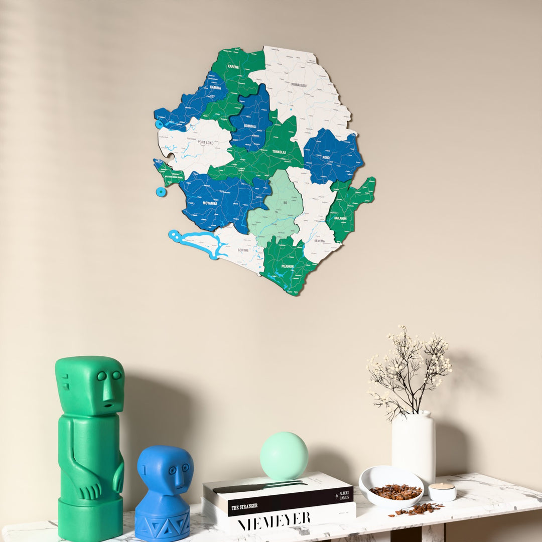 Flag colored Sierra Leone wooden wall map on a beige wall above a console with figurines
