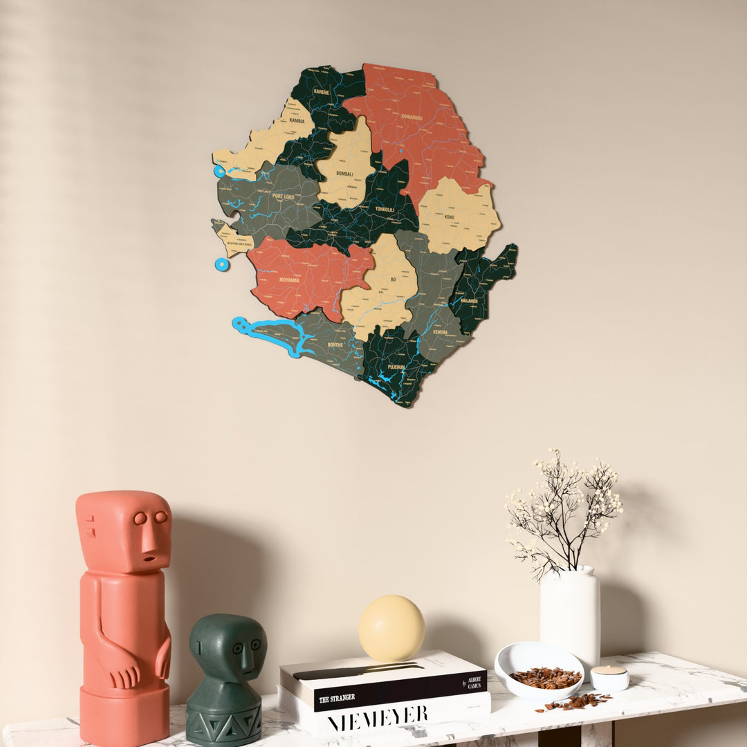 Sage Sierra Leone wooden wall map on a beige wall above a console with figurines