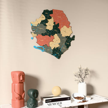 Sage Sierra Leone wooden wall map on a beige wall above a console with figurines