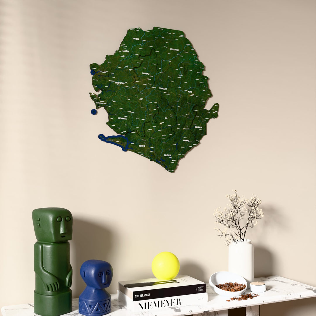 Satellite Sierra Leone wooden wall map on a beige wall above a console with figurines