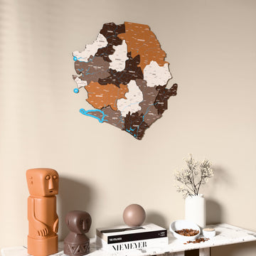 Soil Sierra Leone wooden wall map on a beige wall above a console with figurines
