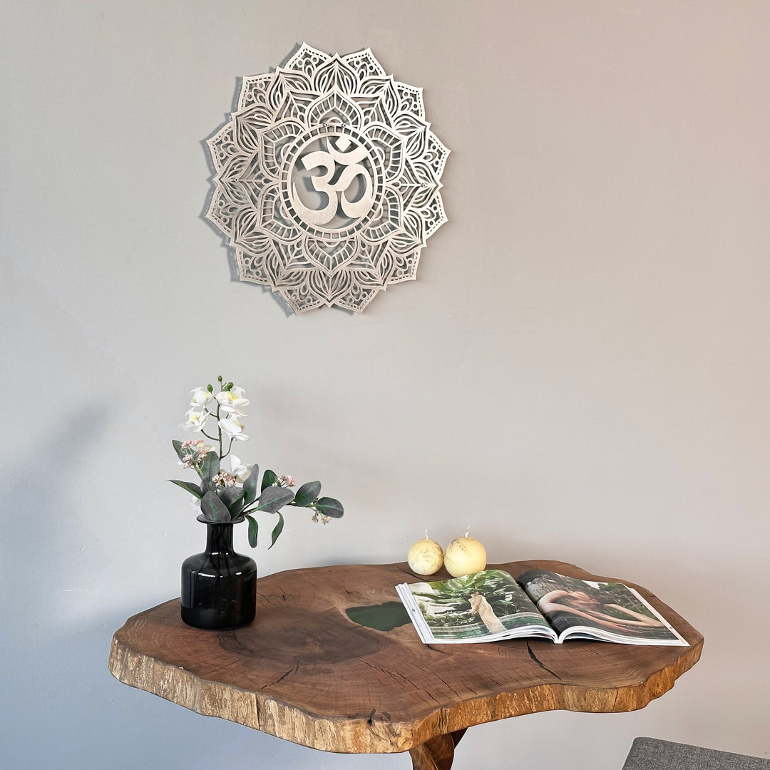 Large silver OM mandala metal wall art close above a live-edge table with two pears