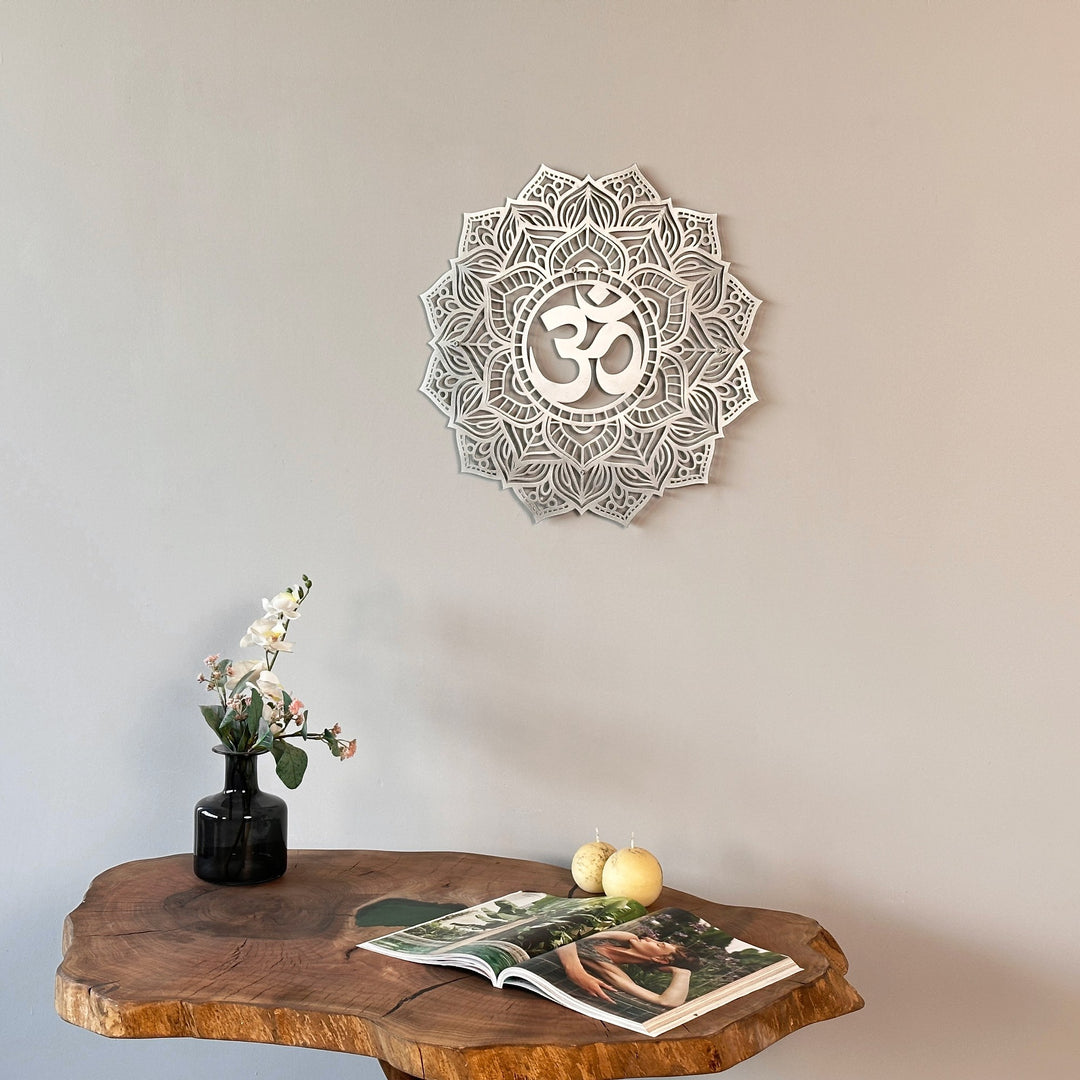 Silver OM mandala metal wall art centered over a live-edge table with a vase of flowers