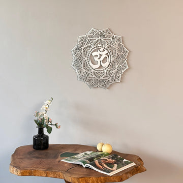 Silver OM mandala metal wall art centered over a live-edge table with a vase of flowers