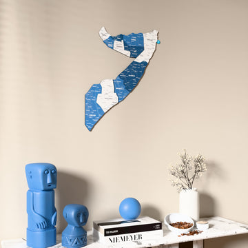 Flag colored Somalia wooden wall map on a beige wall above a console with figurines