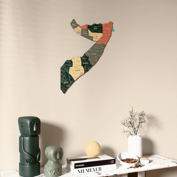 Sage Somalia wooden wall map on a beige wall above a console with figurines