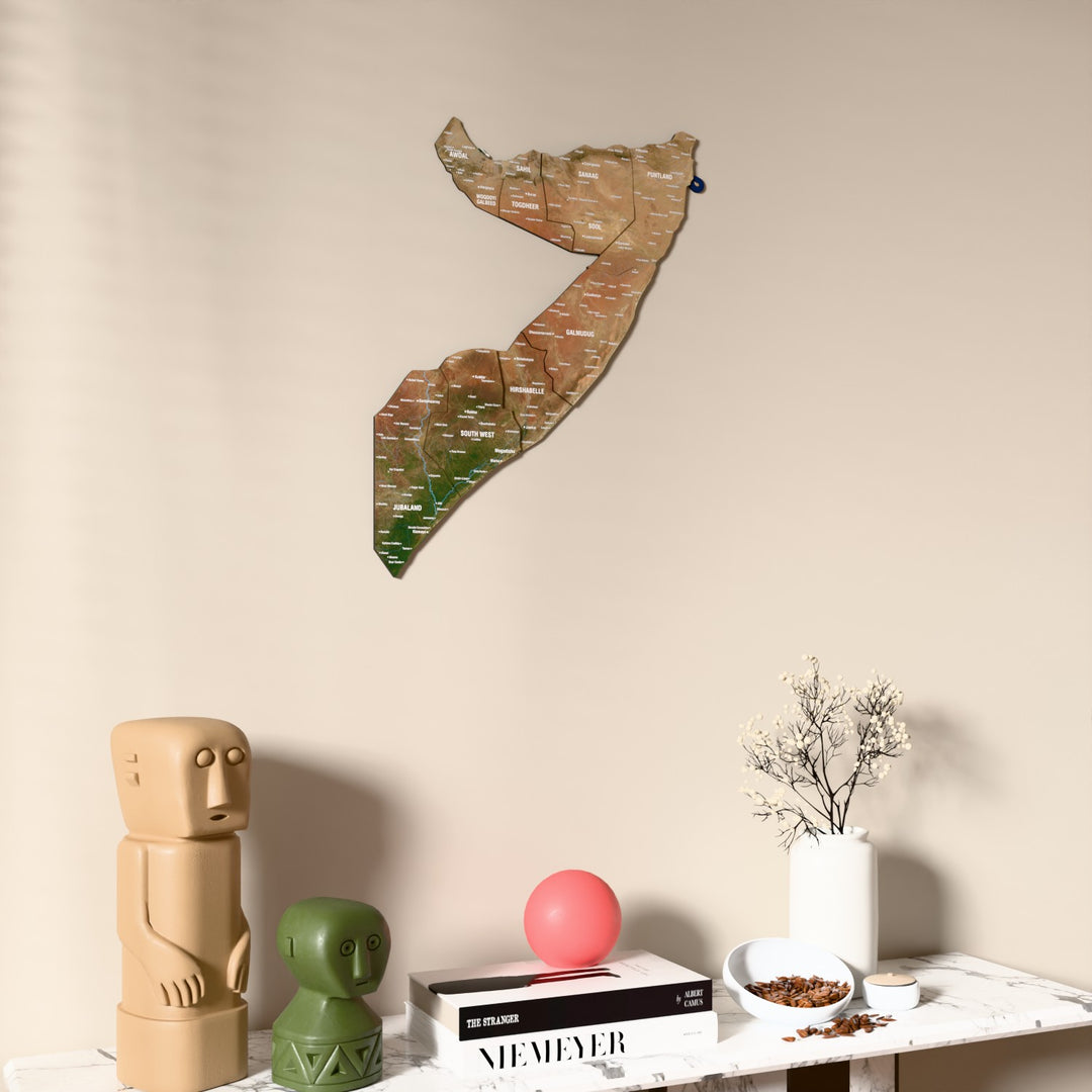 Satellite Somalia wooden wall map on a beige wall above a console with figurines