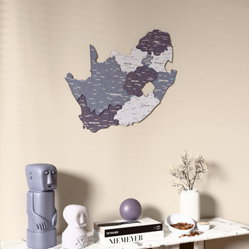Nimbus South Africa wooden wall map on a beige wall above a console with figurines