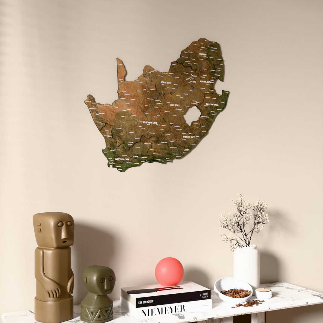 Satellite South Africa wooden wall map on a beige wall above a console with figurines