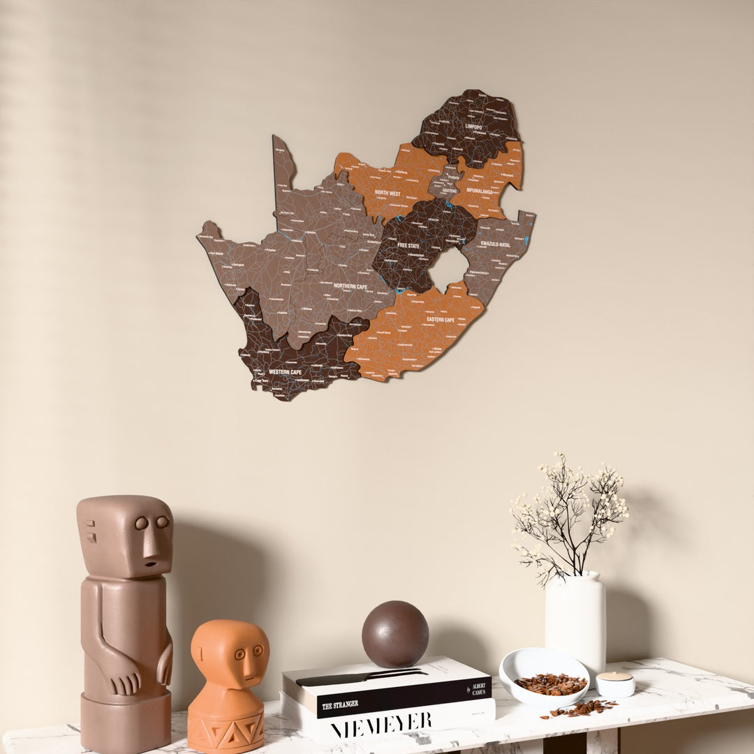 Soil South Africa wooden wall map on a beige wall above a console with figurines