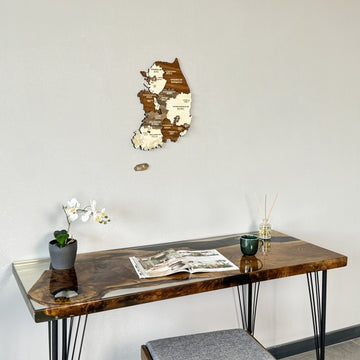 South Korea wooden wall map above the end of a resin desk with an orchid