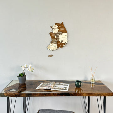 South Korea wooden wall map on a gray wall above a resin desk with an orchid