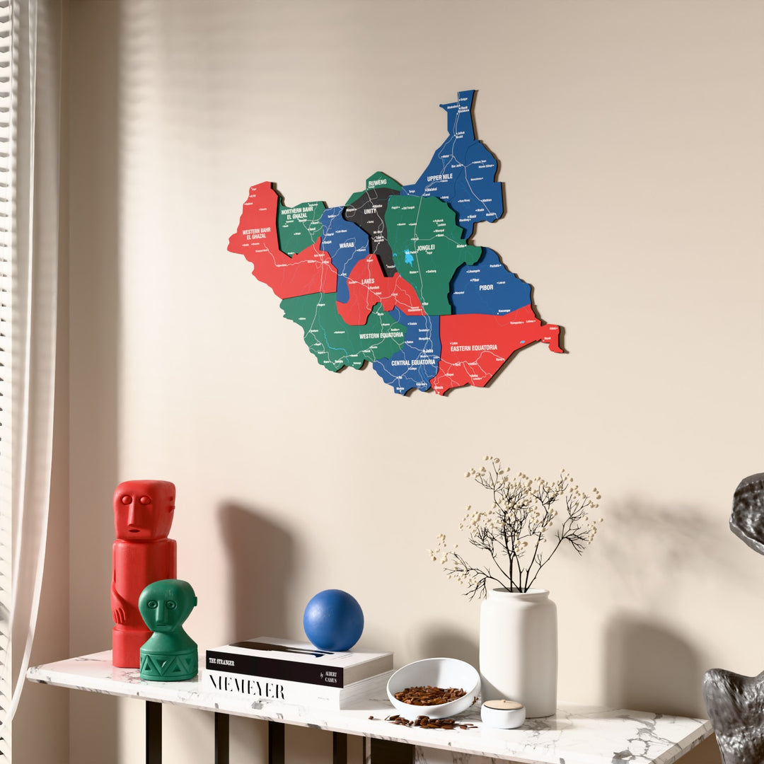 Flag colored South Sudan wooden wall map beside a sheer curtain, angled view