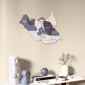Nimbus South Sudan wooden wall map on a beige wall above a console with figurines