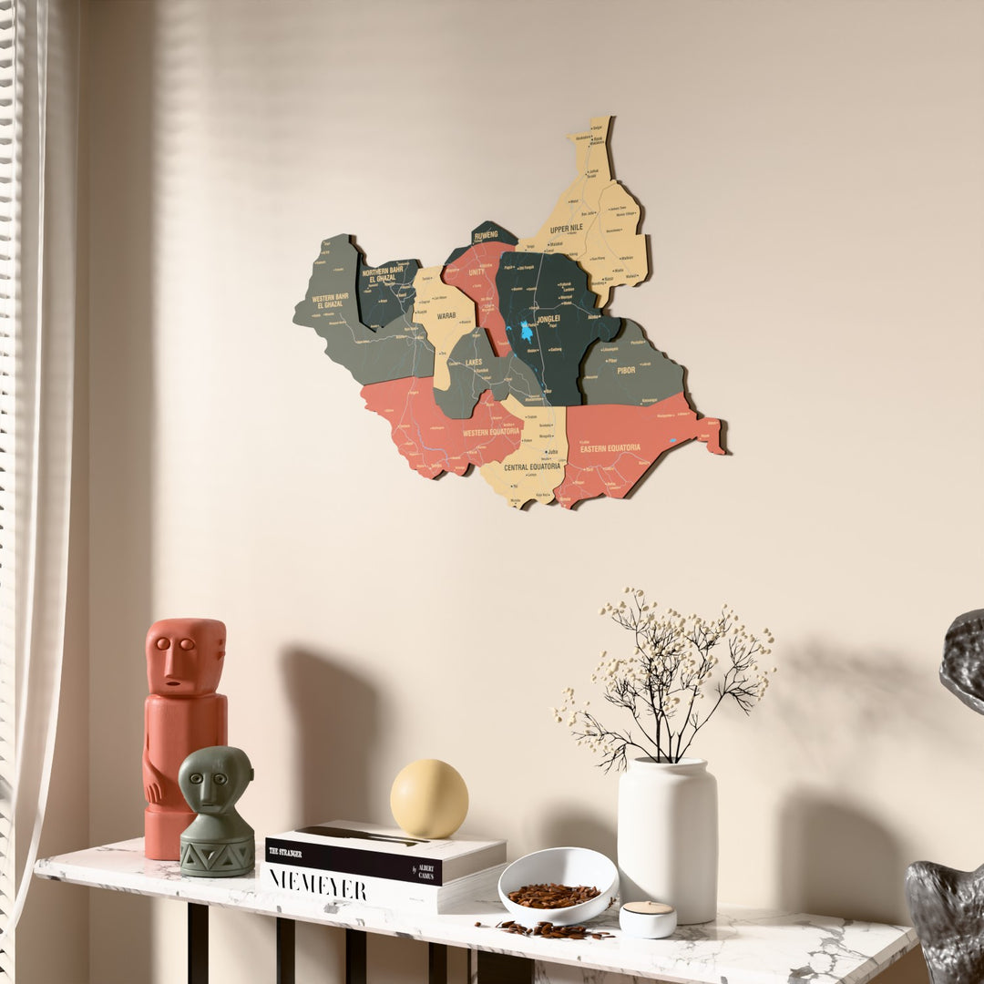 Sage South Sudan wooden wall map beside a sheer curtain, angled view