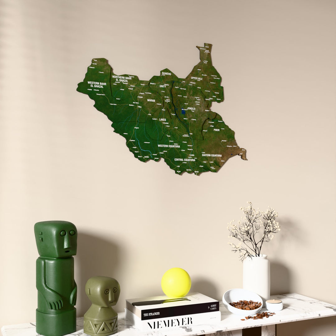 Satellite South Sudan wooden wall map on a beige wall above a console with figurines