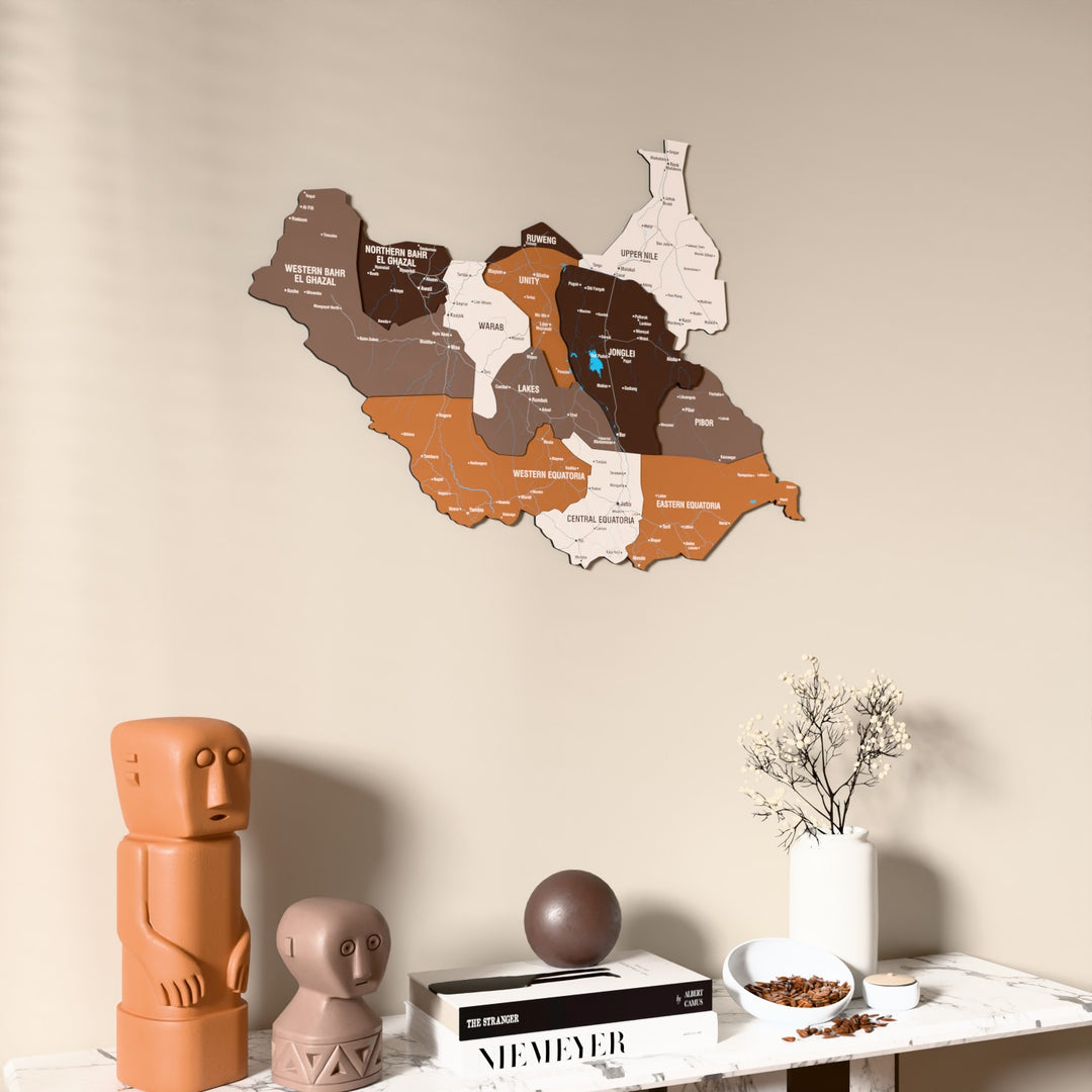 Soil South Sudan wooden wall map on a beige wall above a console with figurines