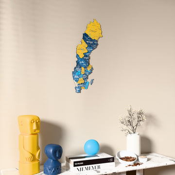 Flag colored Sweden wooden wall map on a beige wall above a console with figurines