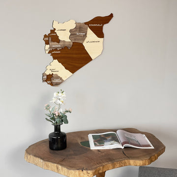 Syria wooden map above a live-edge table with an orchid in a black vase, from the right