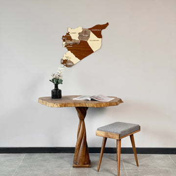 Syria wooden wall map above a live-edge table with a twisted base and a vase of flowers