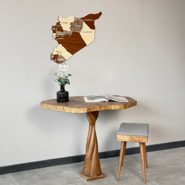 Syria wooden wall map centered above a pedestal table with a gray upholstered stool