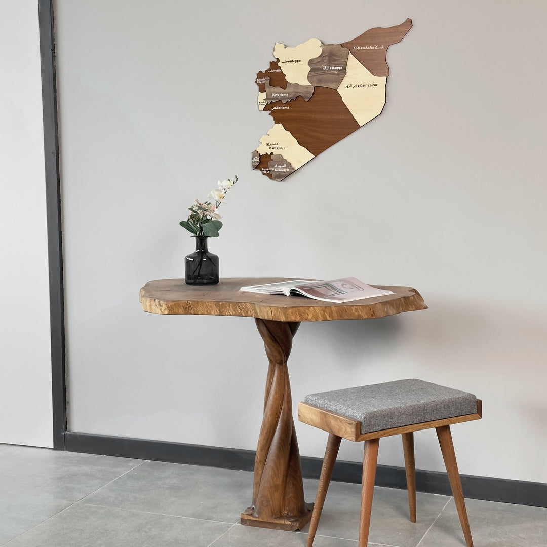 Syria wooden map next to a window frame, above a twisted-base wooden table with a gray stool