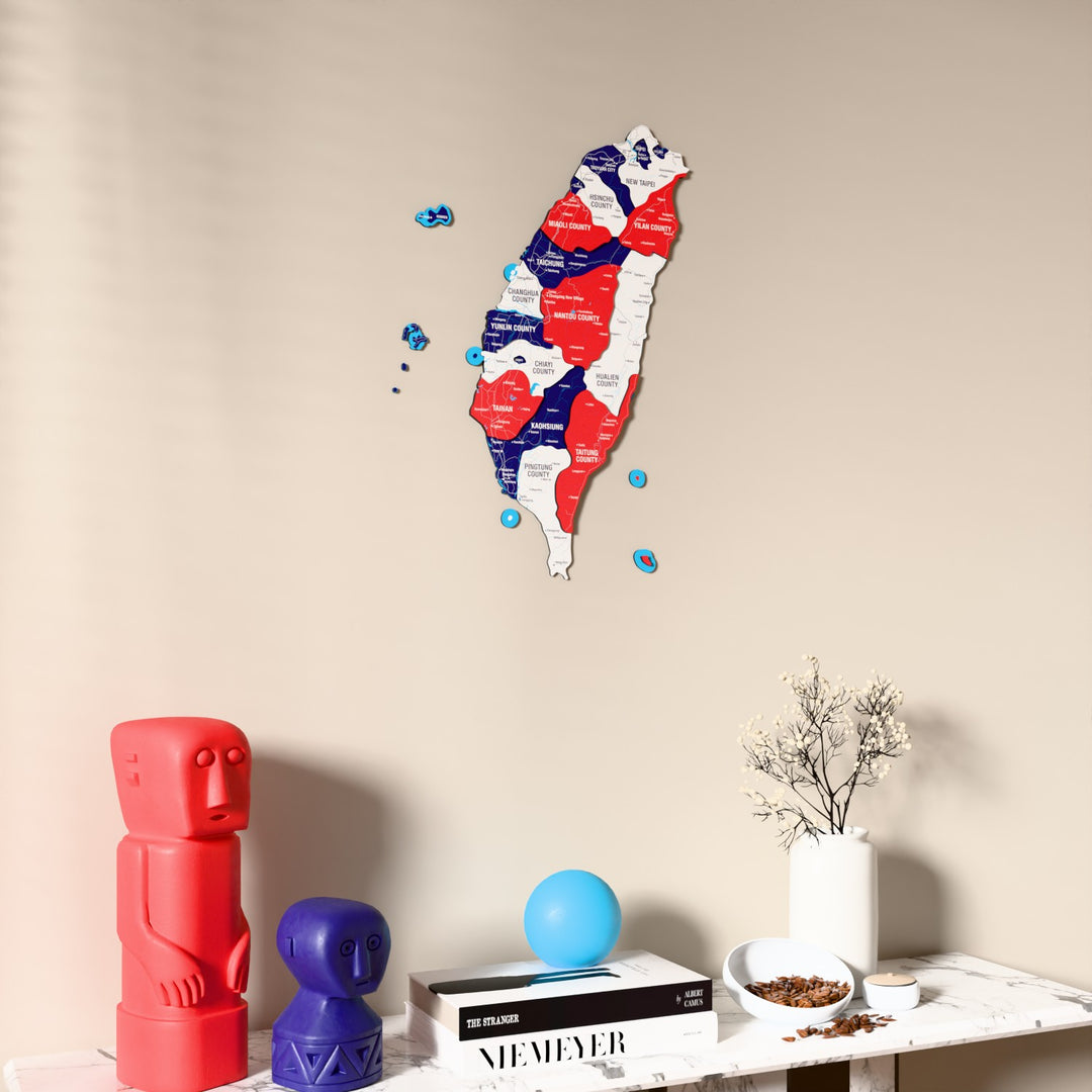 Flag colored Taiwan wooden wall map on a beige wall above a console with figurines