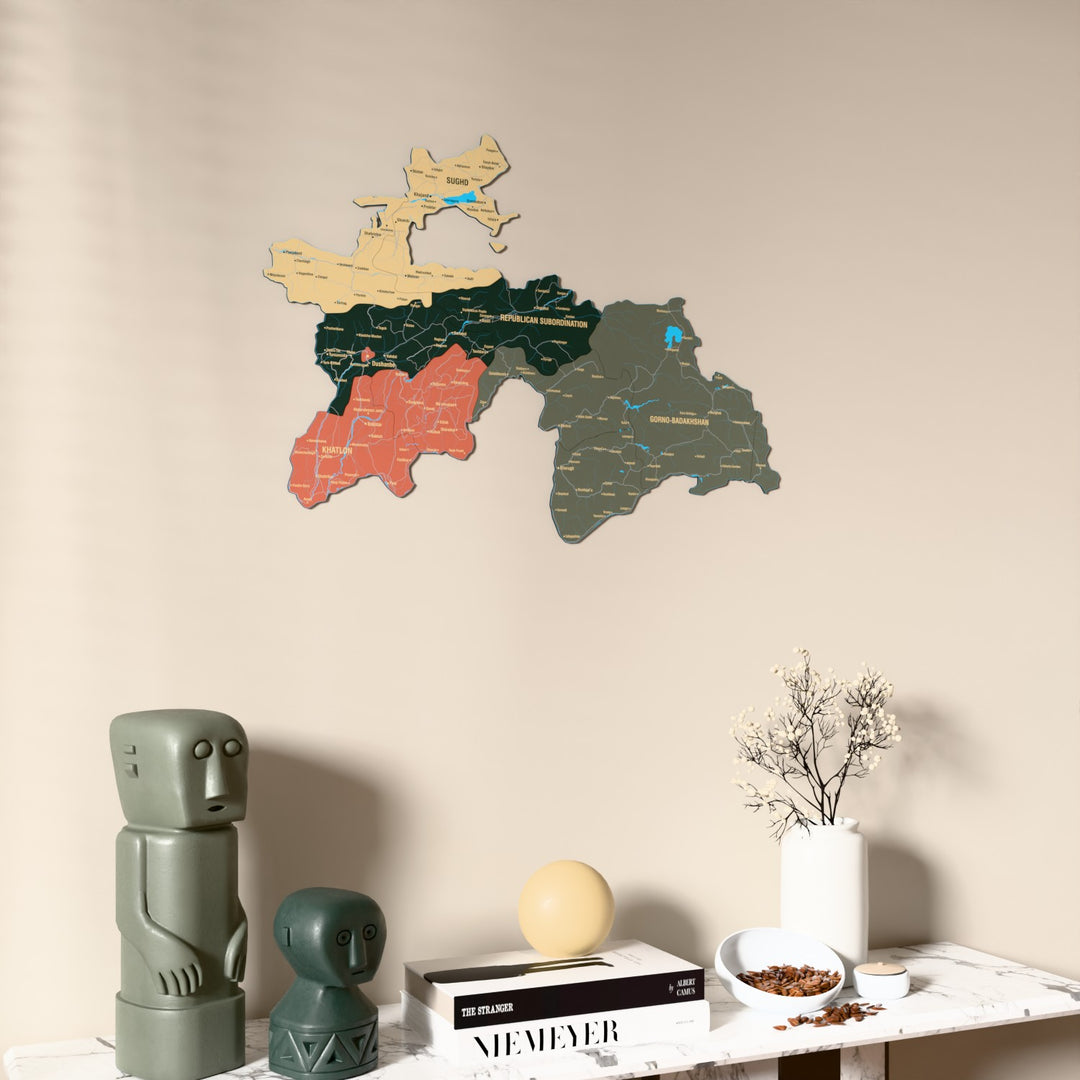 Sage Tajikistan wooden wall map on a beige wall above a console with figurines