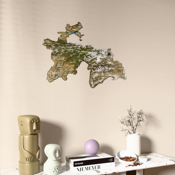 Satellite Tajikistan wooden wall map on a beige wall above a console with figurines