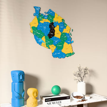 Flag colored Tanzania wooden wall map on a beige wall above a console with figurines