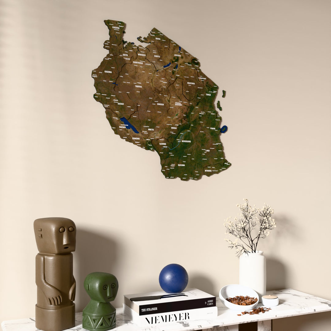 Satellite Tanzania wooden wall map on a beige wall above a console with figurines